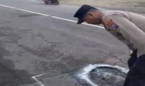 Petugas Polsek Tikung memberi tanda jalan berlubang di Jalan Raya Tikung–Mantup Lamongan