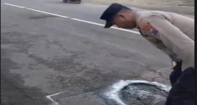 Petugas Polsek Tikung memberi tanda jalan berlubang di Jalan Raya Tikung–Mantup Lamongan