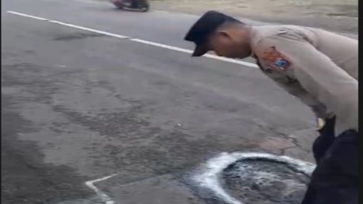 Petugas Polsek Tikung memberi tanda jalan berlubang di Jalan Raya Tikung–Mantup Lamongan