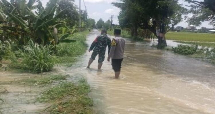 Polsek Tikung memantau genangan air di jalan raya akibat hujan lebat di Kecamatan Tikung Lamongan