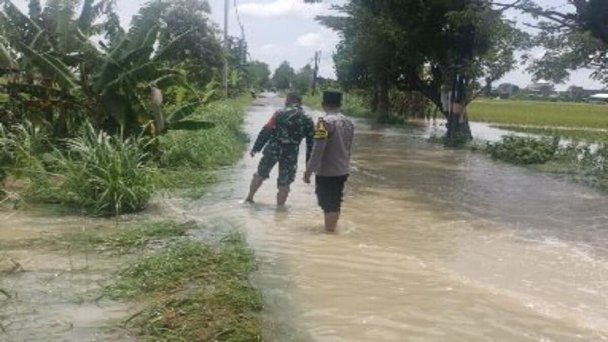Polsek Tikung memantau genangan air di jalan raya akibat hujan lebat di Kecamatan Tikung Lamongan